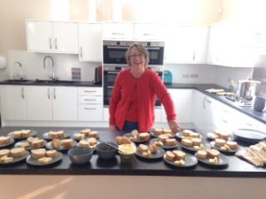 Picture of Teresa In Assumption Church Hall Kitchen with plats of bread at the ready